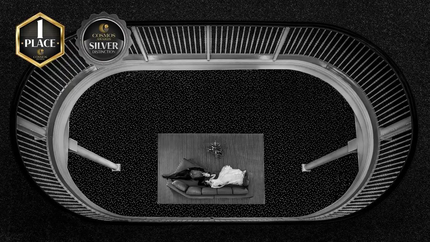 Brautpaar liegt auf einem Sofa, fotografiert von oben durch ein ovales Treppenhaus, schwarz-weiss